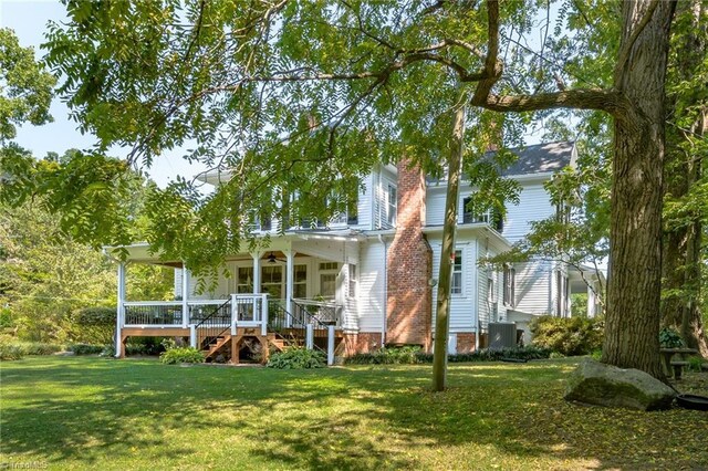 rear view of property featuring a deck and a lawn