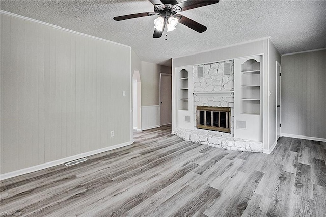 5948 Muddy Creek Rd, Archdale, NC 27263 - unfurnished living room with wood finished floors, a ceiling fan, a textured ceiling, a stone fireplace, and built in shelves