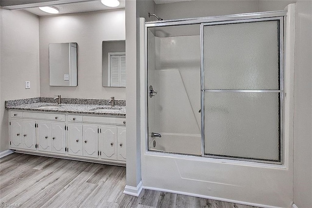 5948 Muddy Creek Rd, Archdale, NC 27263 - full bath featuring wood finished floors, bath / shower combo with glass door, double vanity, and baseboards