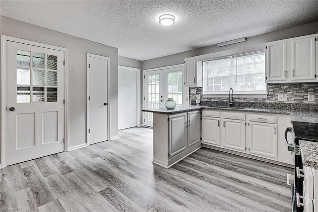 5948 Muddy Creek Rd, Archdale, NC 27263 - kitchen featuring a sink, a peninsula, white cabinets, light wood-style floors, and backsplash