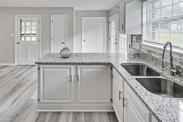 5948 Muddy Creek Rd, Archdale, NC 27263 - kitchen featuring a sink, light wood-style floors, a peninsula, white cabinetry, and light stone counters