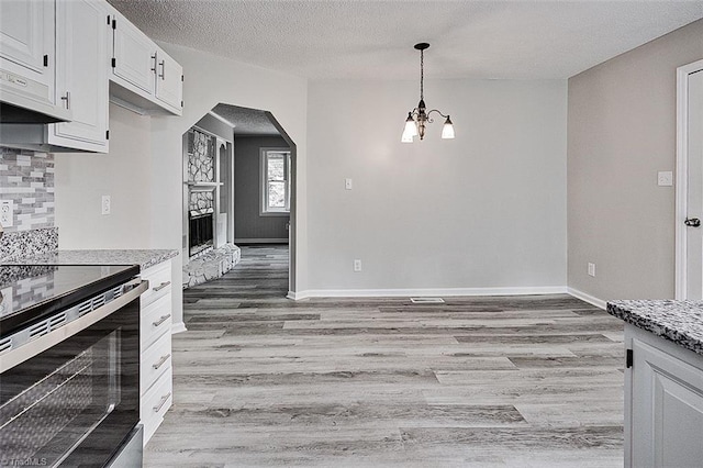 5948 Muddy Creek Rd, Archdale, NC 27263 - kitchen with electric range, light wood-style floors, a chandelier, arched walkways, and a textured ceiling
