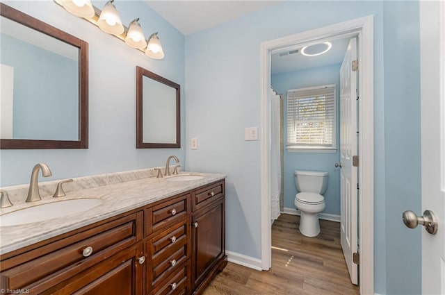 bathroom with wood finished floors, a sink, visible vents, and baseboards