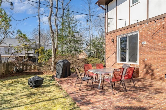 view of patio featuring a fire pit, outdoor dining space, area for grilling, and fence