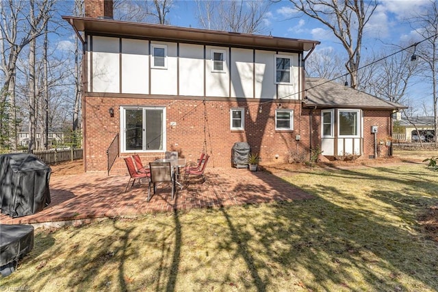 back of house with a lawn, a patio, a chimney, fence, and brick siding