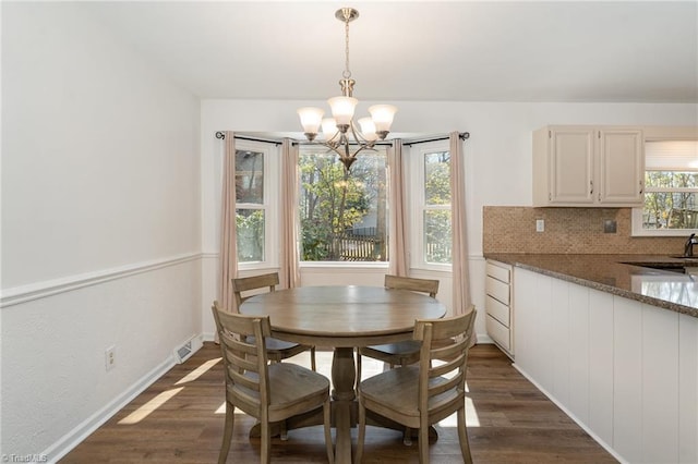 dining space with baseboards, dark wood finished floors, visible vents, and an inviting chandelier