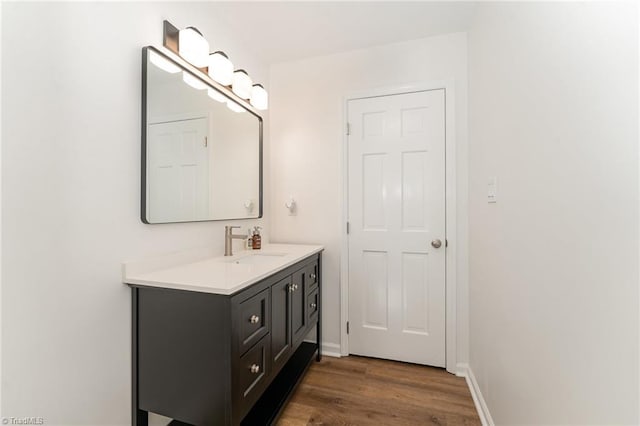 bathroom with wood finished floors, vanity, and baseboards