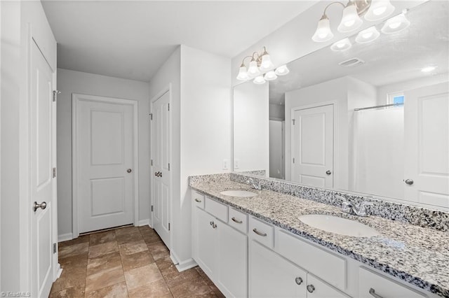 635 Cam Cir, High Point, NC 27265 - bathroom featuring baseboards, a chandelier, double vanity, and stone finish floors