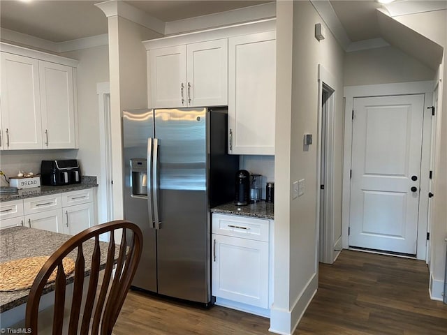 kitchen with dark stone counters, dark hardwood / wood-style flooring, white cabinets, stainless steel refrigerator with ice dispenser, and crown molding