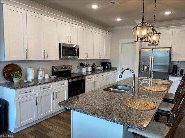 kitchen featuring sink, a kitchen bar, an inviting chandelier, stainless steel appliances, and a center island with sink