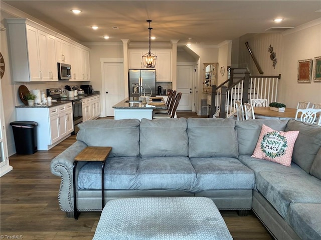 living room featuring crown molding, sink, and dark wood-type flooring