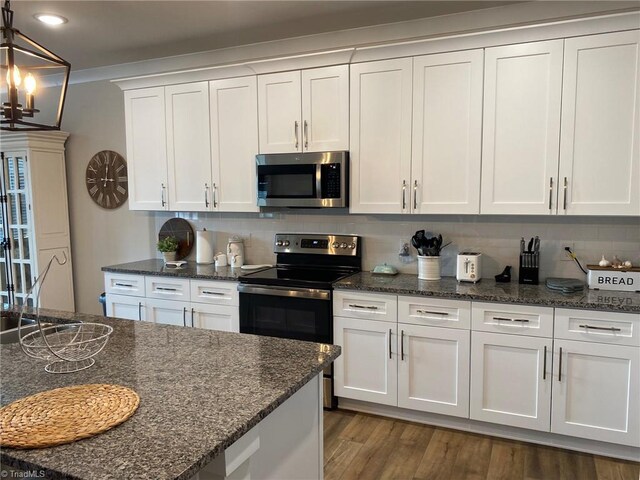 kitchen featuring a notable chandelier, stainless steel appliances, white cabinets, and dark wood-type flooring