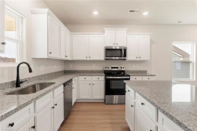 239 Dixieland Ct, King, NC 27021 - kitchen featuring appliances with stainless steel finishes, white cabinets, plenty of natural light, recessed lighting, and light wood-style floors
