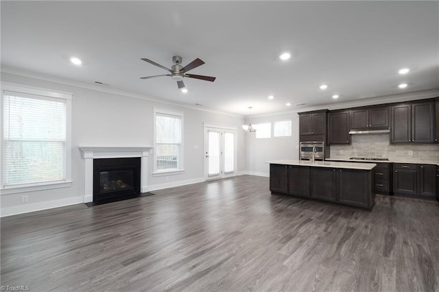 kitchen featuring hanging light fixtures, dark hardwood / wood-style floors, a center island with sink, ceiling fan with notable chandelier, and ornamental molding