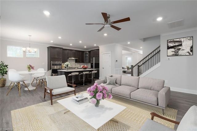 living room with hardwood / wood-style flooring, ceiling fan with notable chandelier, and ornamental molding