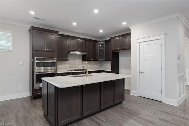 kitchen featuring a center island with sink, ornamental molding, sink, and appliances with stainless steel finishes