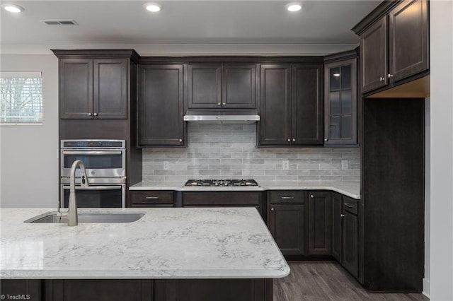 kitchen featuring sink, dark wood-type flooring, backsplash, crown molding, and appliances with stainless steel finishes