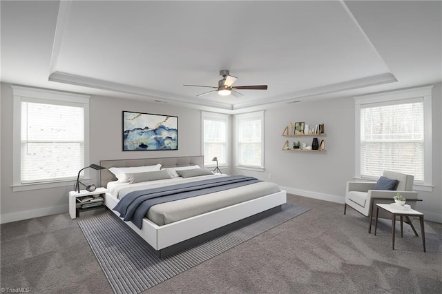 carpeted bedroom featuring a tray ceiling and ceiling fan