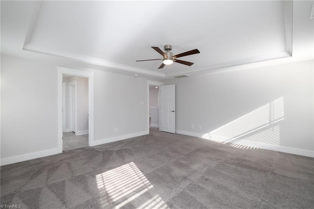 carpeted spare room with a tray ceiling and ceiling fan