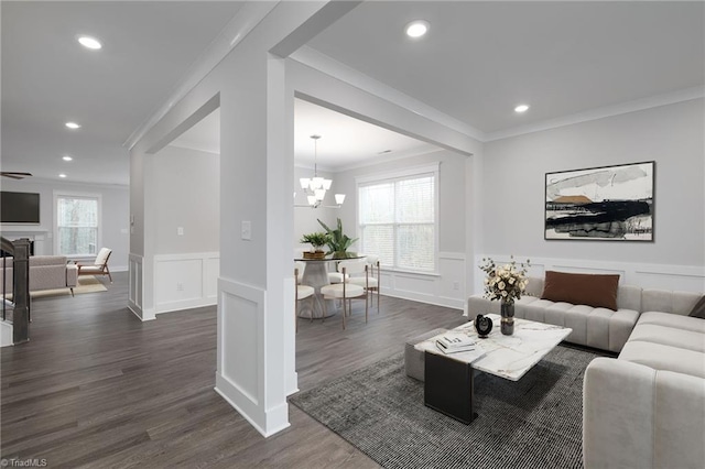 living room featuring an inviting chandelier, crown molding, and dark wood-type flooring