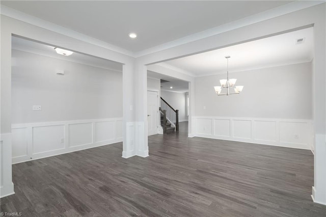 spare room featuring dark hardwood / wood-style floors, crown molding, and an inviting chandelier