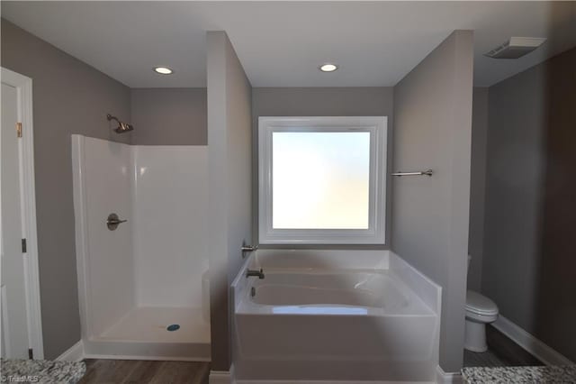 bathroom with hardwood / wood-style flooring, toilet, and shower with separate bathtub