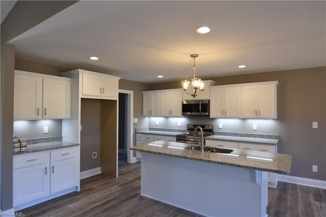 kitchen with dark wood-type flooring, a kitchen island with sink, stainless steel appliances, and white cabinets