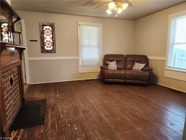 living room featuring dark wood-type flooring, ceiling fan, ornamental molding, and a textured ceiling