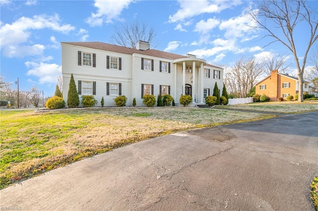 neoclassical / greek revival house with a front yard and a chimney