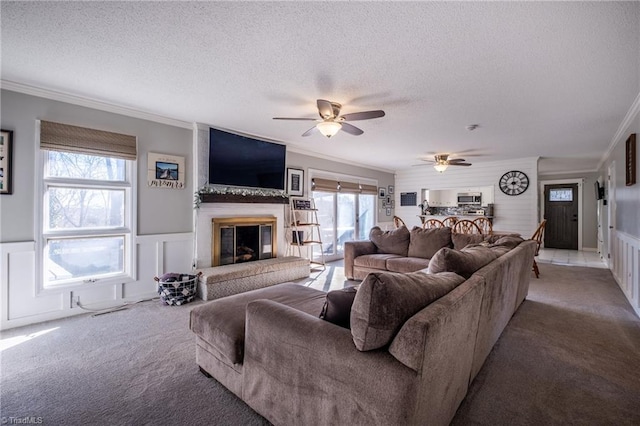 living area featuring a large fireplace, carpet flooring, and crown molding