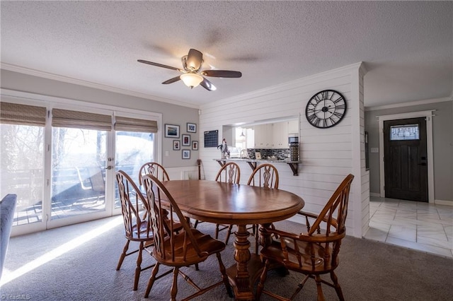 dining area featuring light carpet, ceiling fan, ornamental molding, and a textured ceiling