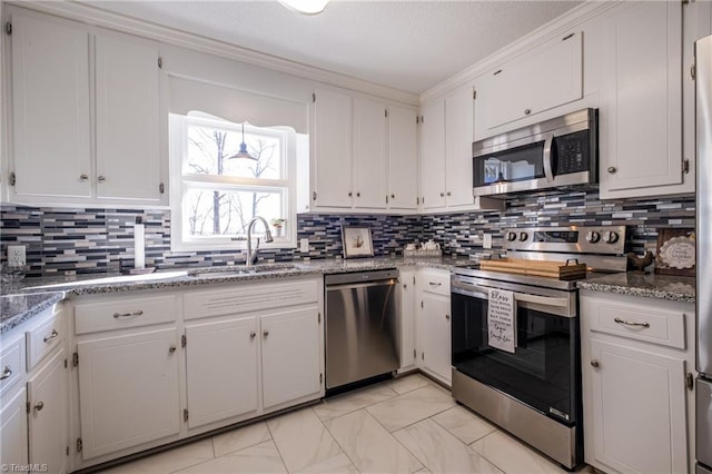 kitchen with stone countertops, decorative backsplash, stainless steel appliances, white cabinetry, and a sink