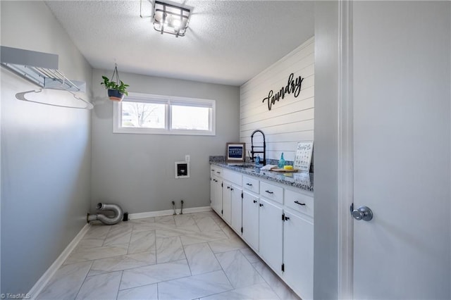 laundry area with a textured ceiling, washer hookup, a sink, marble finish floor, and cabinet space