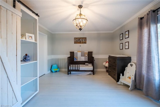 bedroom with an inviting chandelier, a barn door, ornamental molding, and wood finished floors