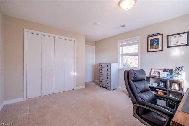 office space featuring baseboards, visible vents, and light colored carpet