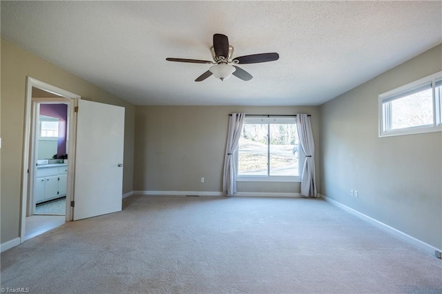 empty room with a textured ceiling, a healthy amount of sunlight, and light colored carpet