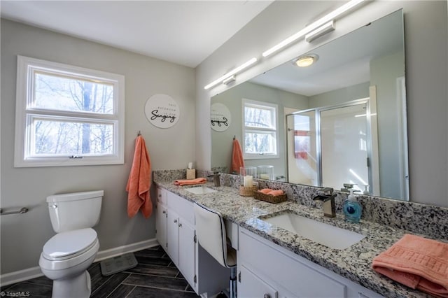 full bathroom with double vanity, a stall shower, baseboards, and a sink