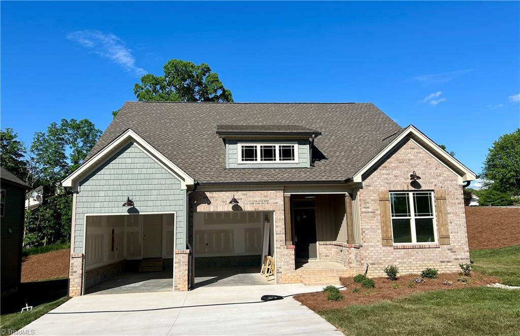 view of front of house featuring brick siding, an attached garage, driveway, and a shingled roof