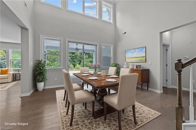 dining area featuring dark wood finished floors, a high ceiling, stairs, and baseboards