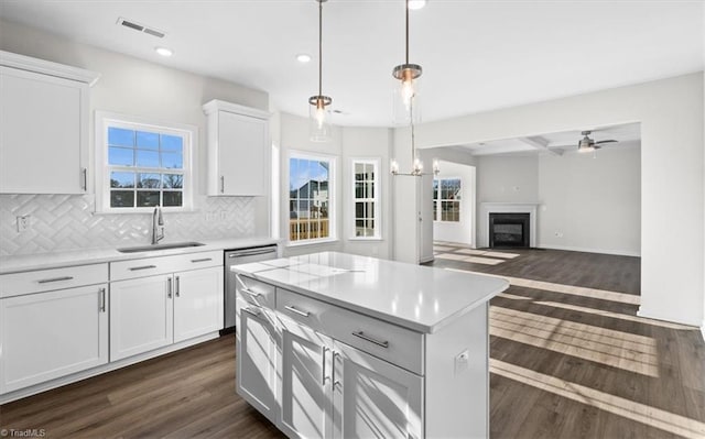 kitchen with sink, white cabinetry, decorative light fixtures, stainless steel dishwasher, and a kitchen island