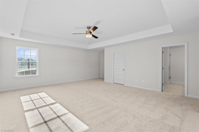 carpeted empty room featuring ceiling fan and a tray ceiling