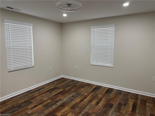 empty room with dark wood-style floors, visible vents, recessed lighting, and baseboards