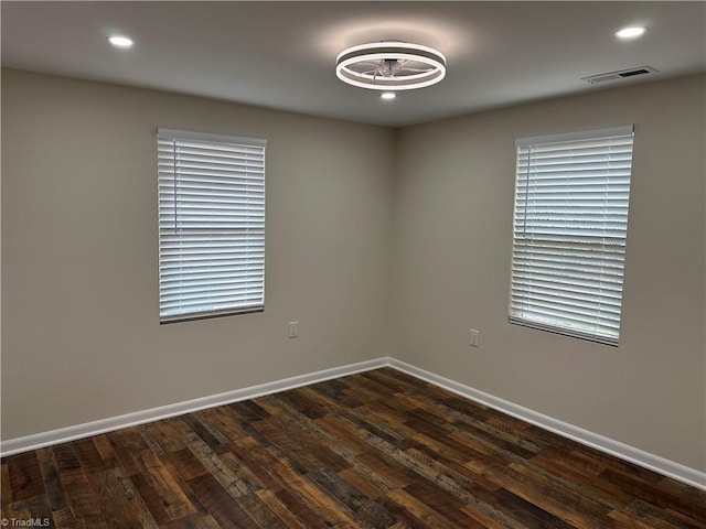 spare room with recessed lighting, visible vents, baseboards, and dark wood finished floors