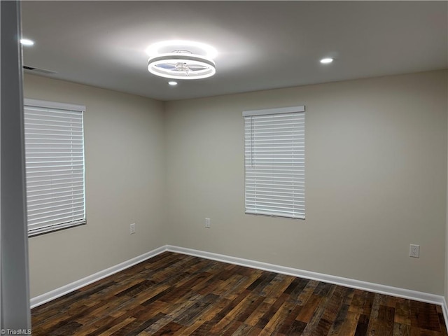 spare room featuring dark wood finished floors, recessed lighting, and baseboards