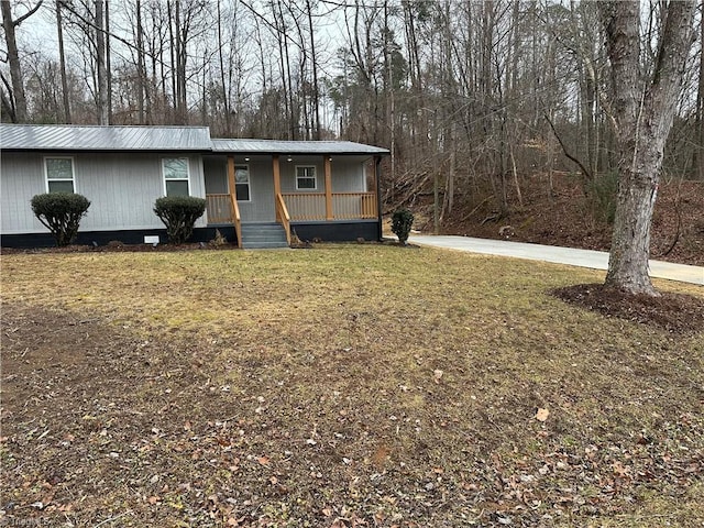 view of front of property with a porch, metal roof, and a front lawn