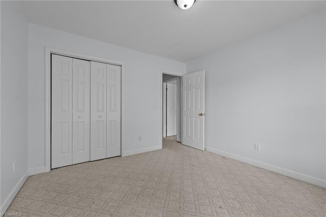 unfurnished bedroom with carpet flooring, baseboards, and a closet