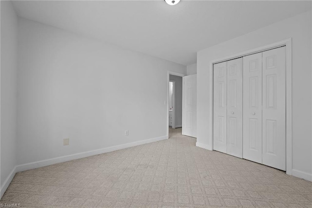 unfurnished bedroom with baseboards, light colored carpet, and a closet