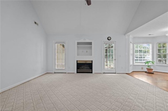 unfurnished living room featuring baseboards, a glass covered fireplace, and carpet