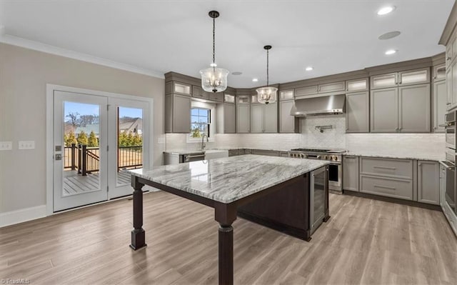 kitchen with gray cabinets, extractor fan, stainless steel range, light wood-type flooring, and backsplash