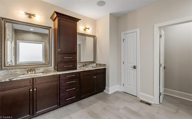 full bathroom with double vanity, baseboards, visible vents, and a sink